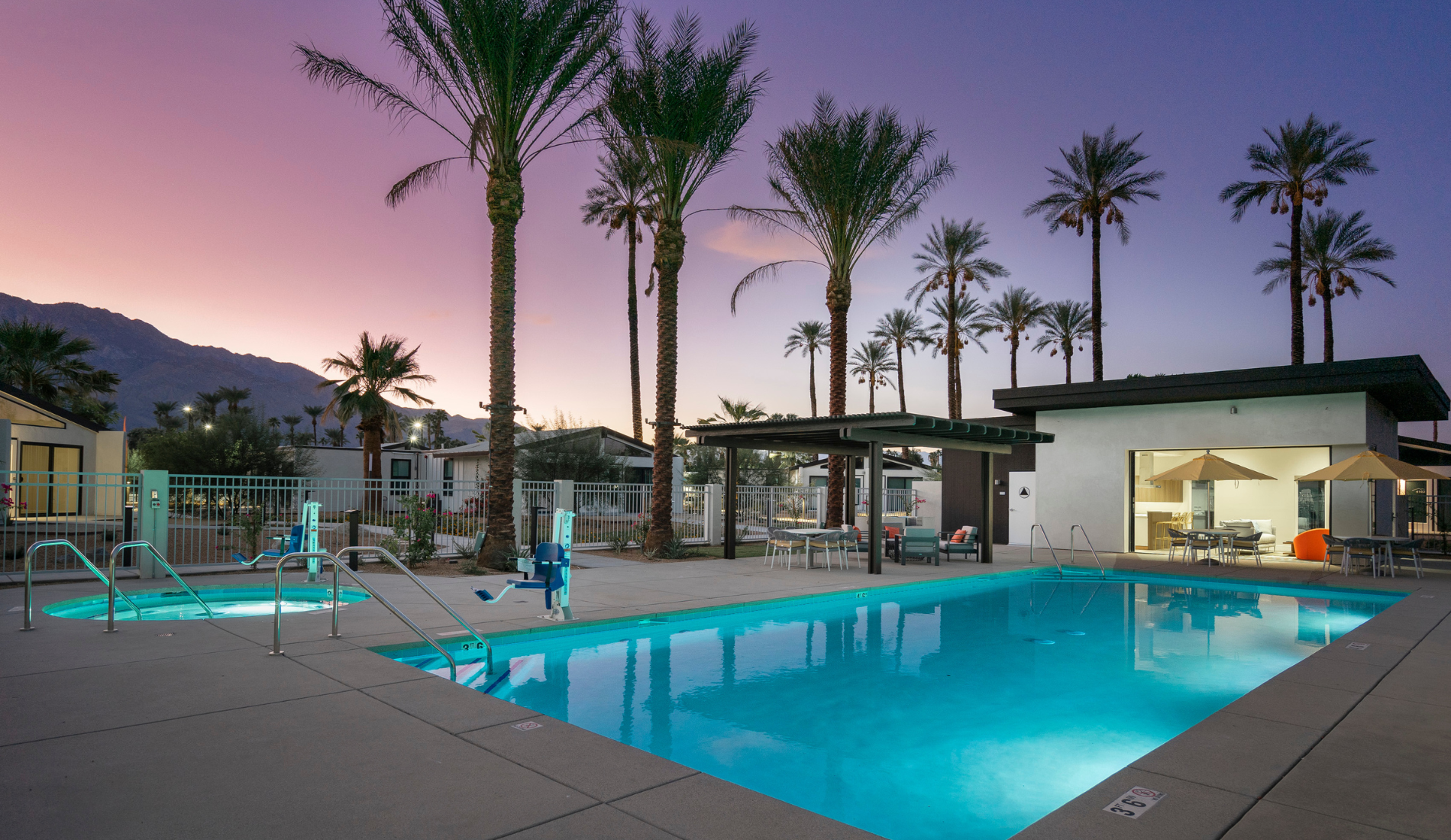 Palm Springs luxury modern resort, pool at dusk with palm trees and buildings