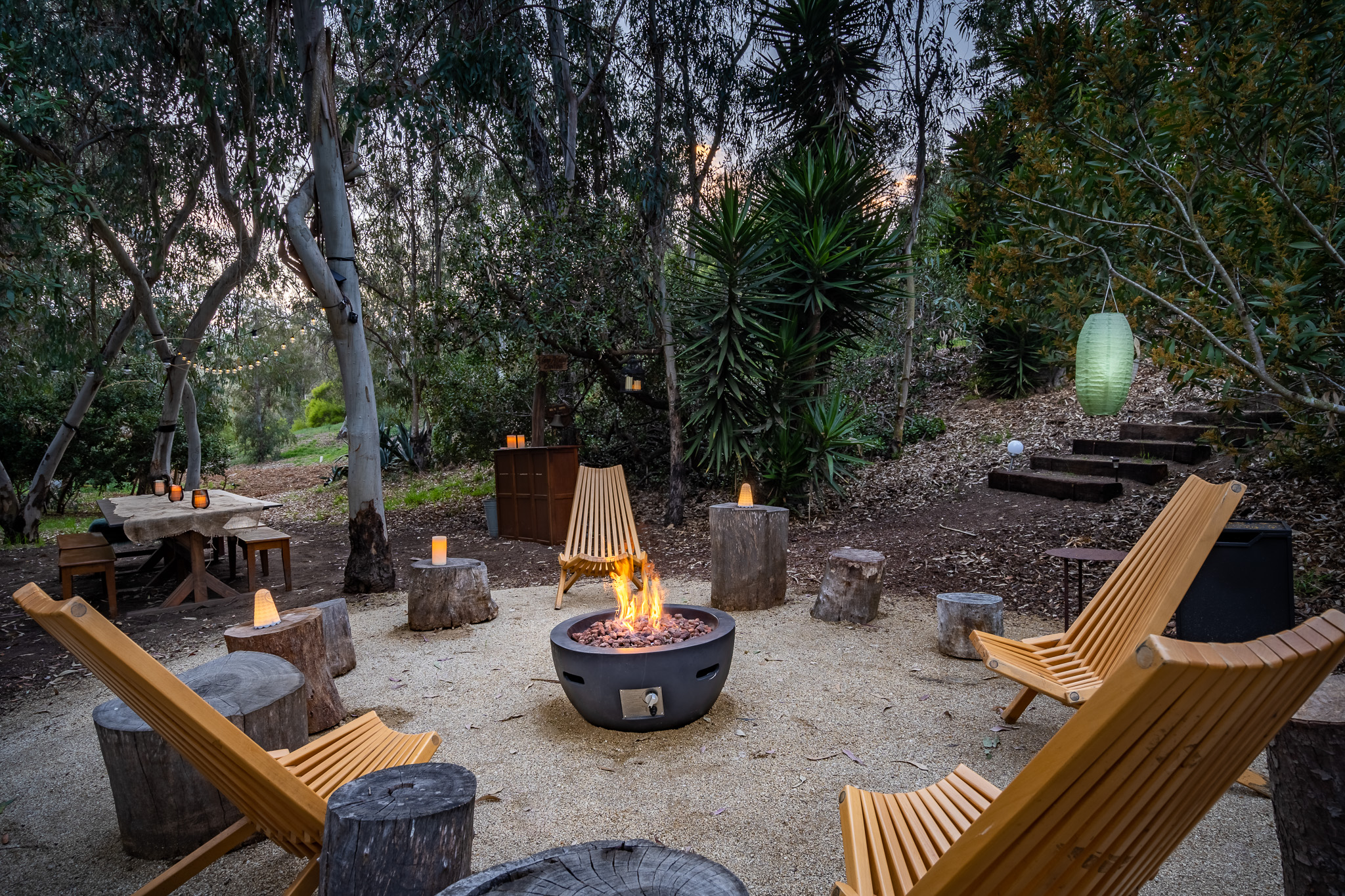 exterior seating area with chairs and fireplace, outdoor meeting and communal area with trees and plants