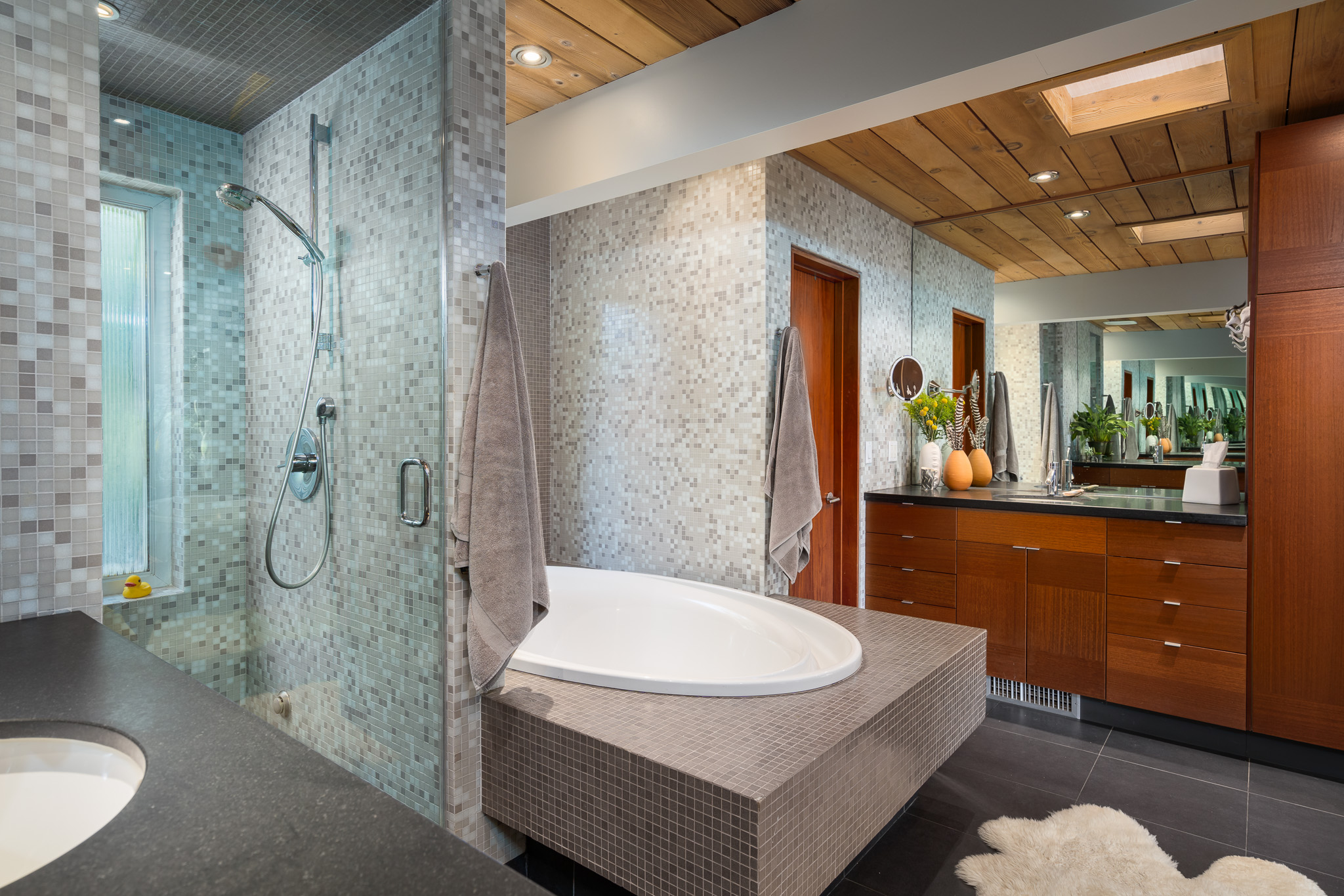 interior design bathroom with tiled shower and bathtub, wood cupboards and storage, mirror