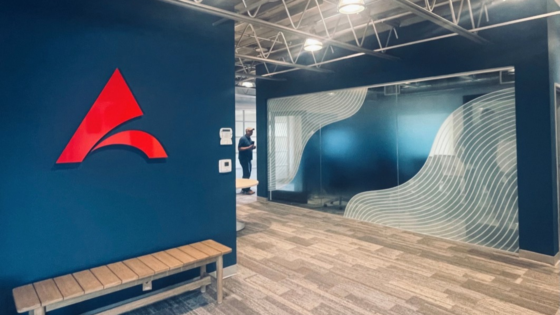 San Diego interior design of office space with red logo on blue wall, bench, flooring, blue and white wave design on conference room