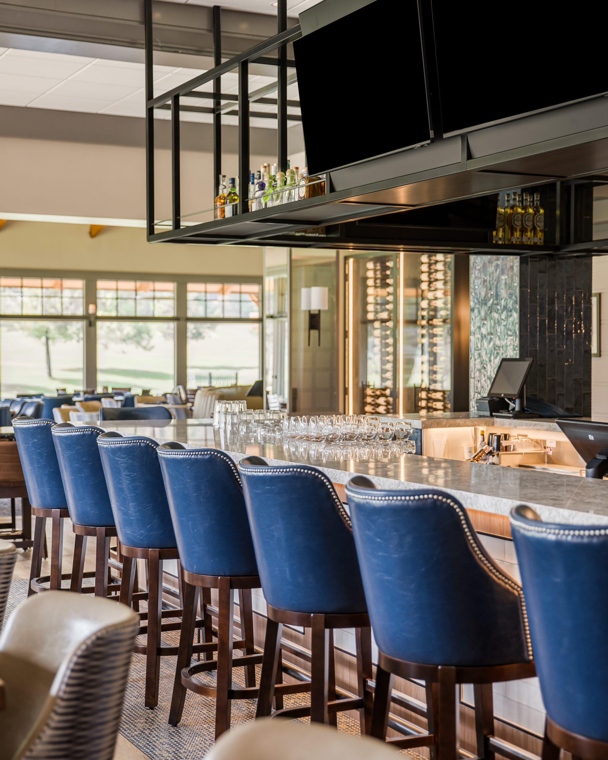 Upscale country club bar and restaurant interior design, blue chair seating, black shelves, glasswear