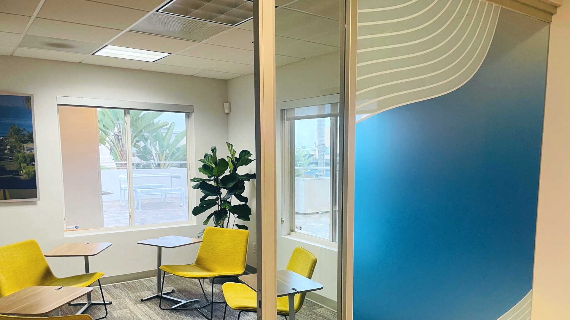 San Diego interior design office space with blue and white screen on glass door, yellow chairs and tables inside meeting room