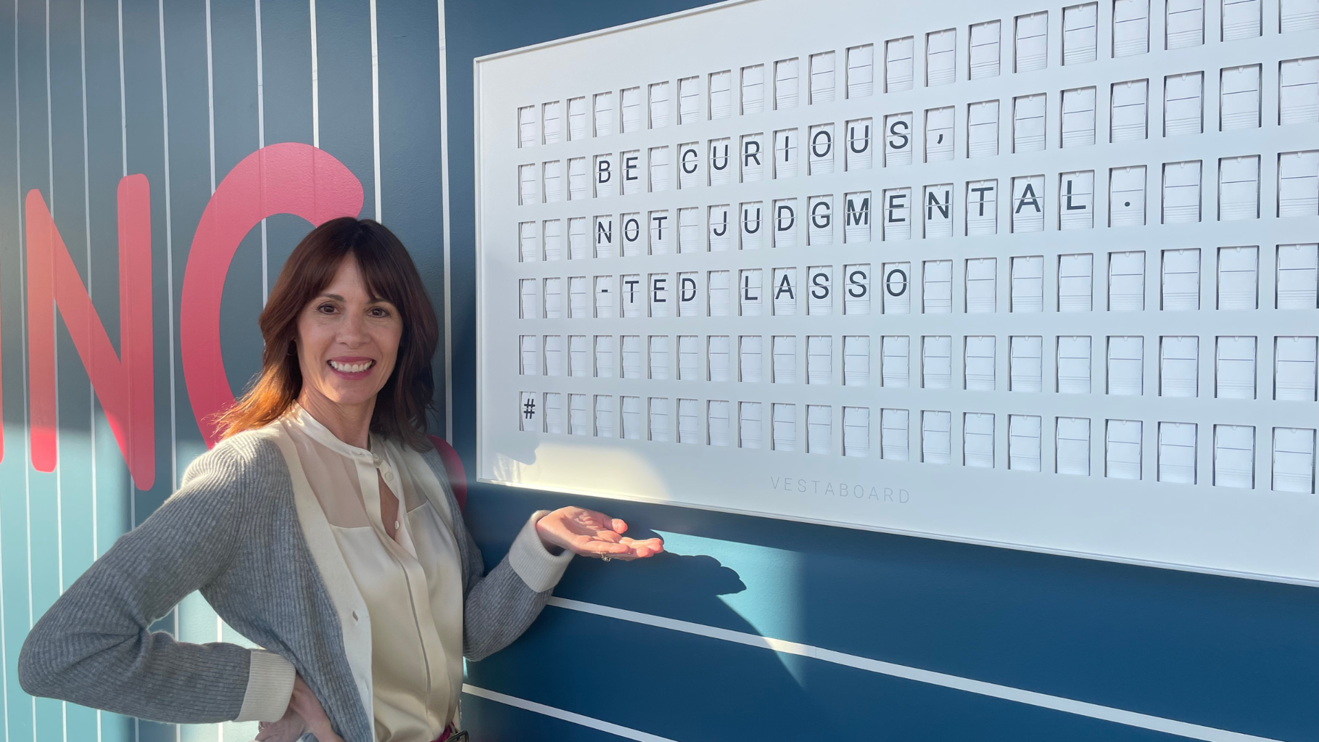 Woman standing next to interior design wall art featuring white board with letters and words