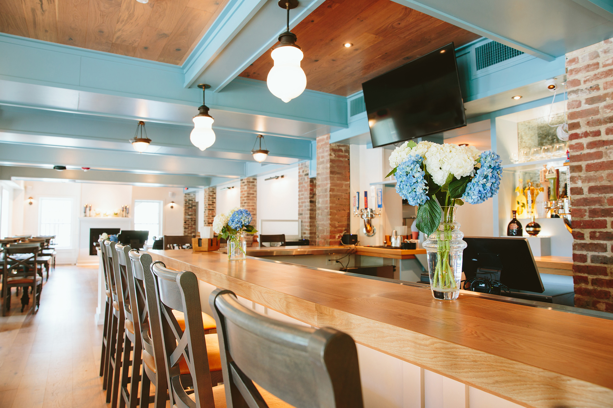 Custom modern tavern and pub interior design and furnishing, with bar, chairs, television, and lighting